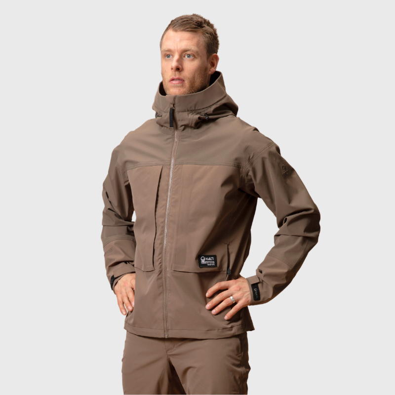 Ein Mann trägt eine Halti Hiker II DrymaxX Regenjacke Herren und eine passende Hose und steht mit der linken Hand auf der Hüfte.