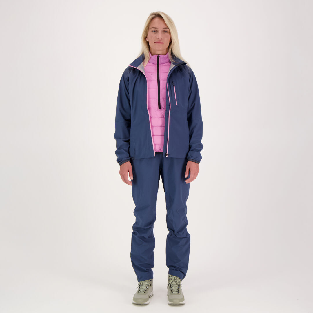 Eine Person blickt nach vorne und trägt eine Halti Liike Damen 3L DrymaxX Sporthose, eine blaue Jacke, einen rosa Reißverschluss und helle Schuhe.
