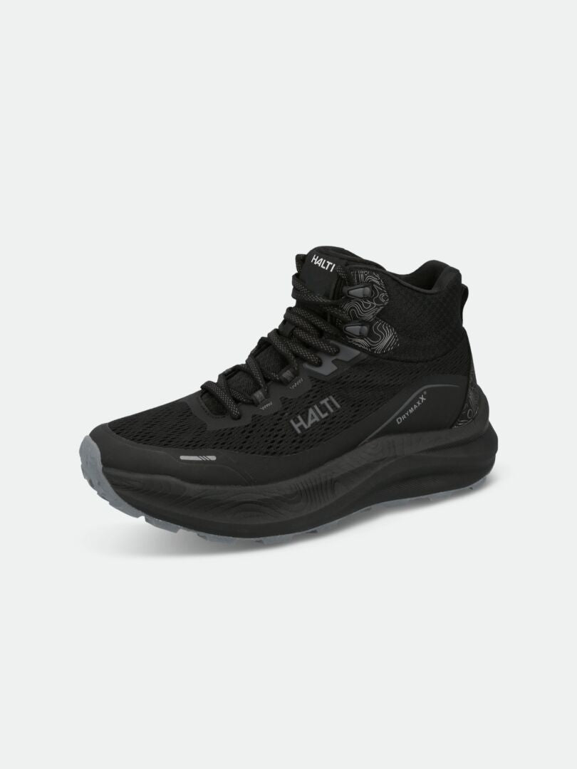Die Halti Rapid DX Mid Outdoor Schuhe Damen in schwarz zeichnen sich durch einen mittelhohen Knöchel und eine dicke Sohle auf hellem Grund aus.