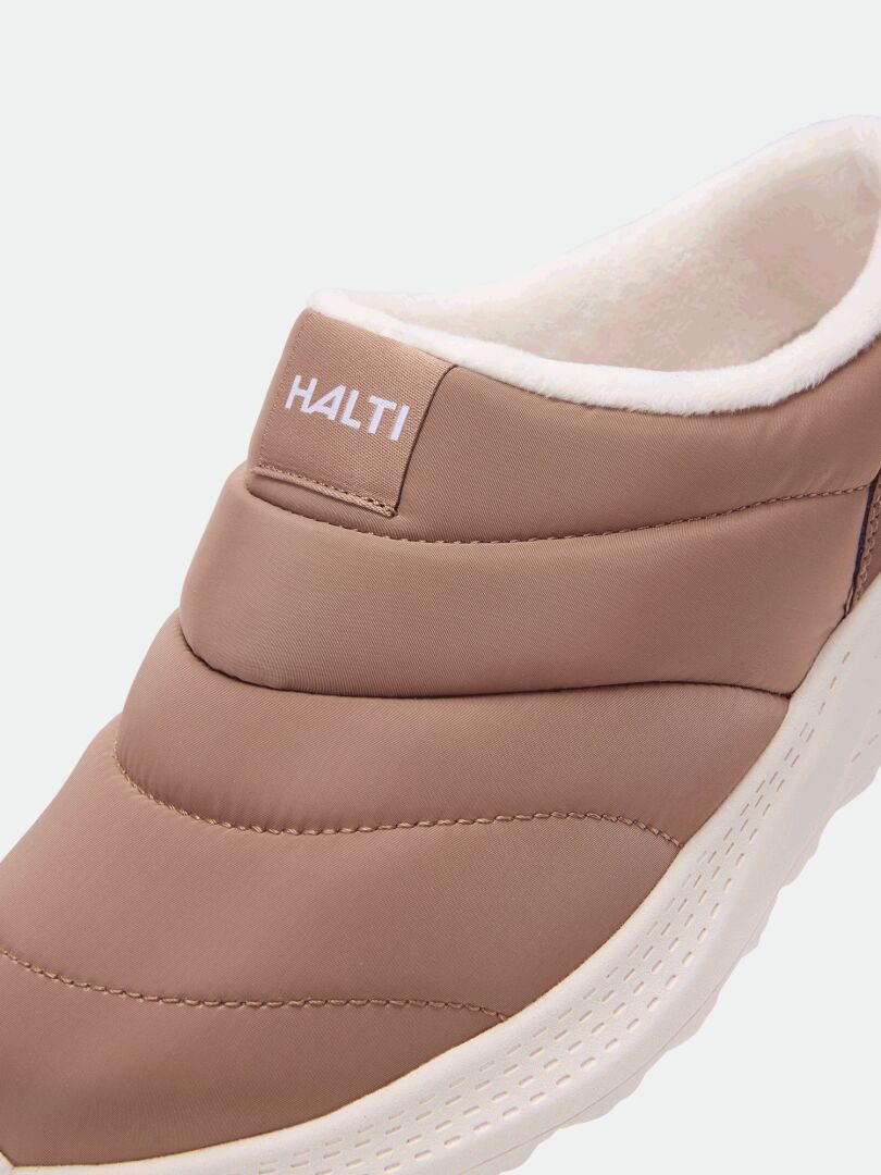 Nahaufnahme eines braunen Halti Rest 2-Hausschuhs mit gestepptem Design, weißer EVA-Sohle und einem HALTI-Etikett auf der Vorderseite.
