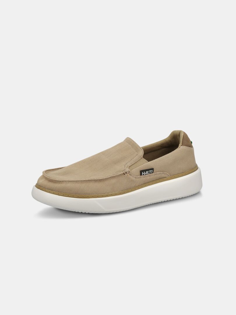 Die Lido Canvas Schuhe Herren von Halti: hellbraune Slipper mit weißer Sohle und Logo-Tag, abgebildet auf weißem Hintergrund.