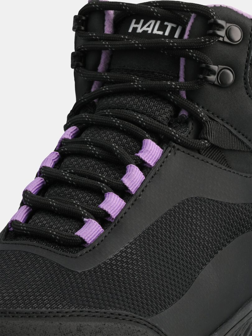 Nahaufnahme des Halti Tuntuma Mid DX Barfußschuhs für Damen in Schwarz, mit violetten Schnürösen und Markenlogo auf der Zunge.