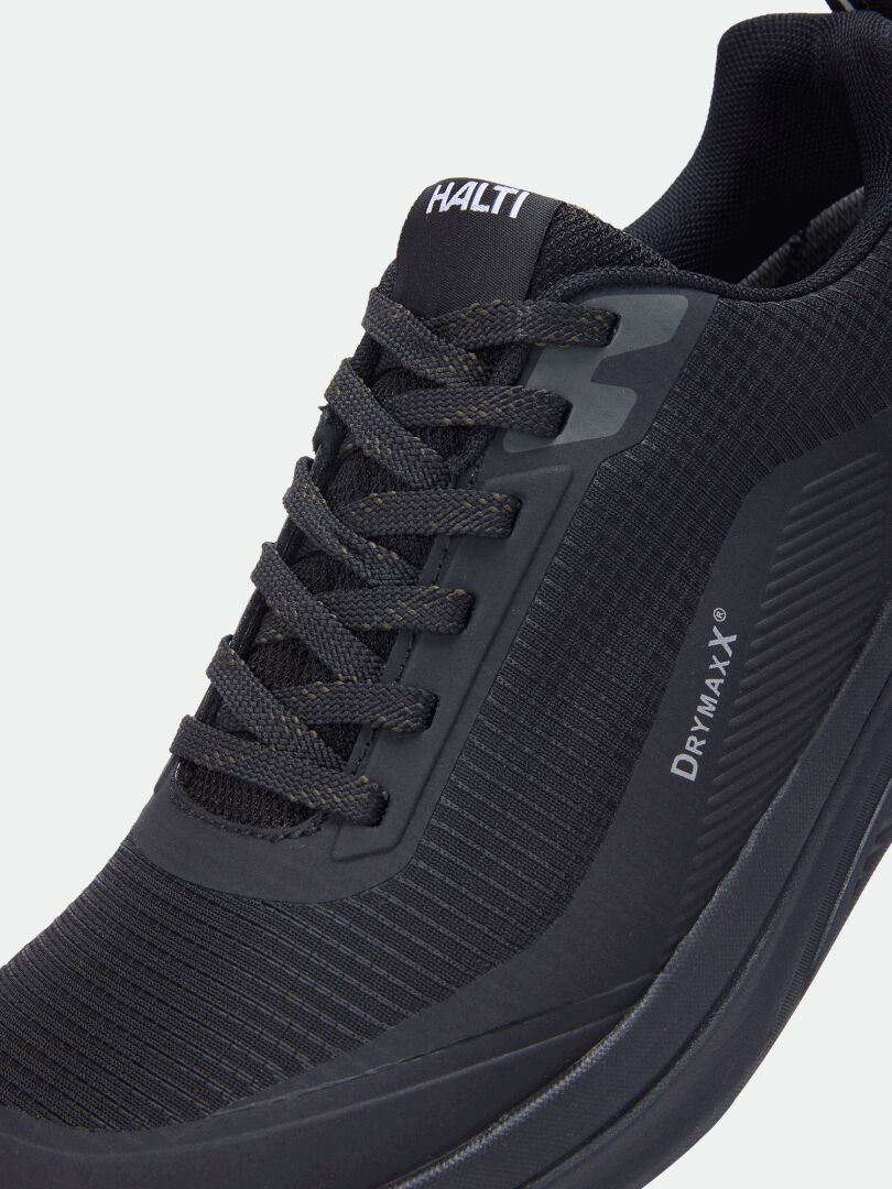 Nahaufnahme der schwarzen Halti Asento DX Outdoor-Schuhe für Herren mit dem „Halti“-Logo auf der Zunge und dem Schriftzug „DrymaxX“ an der Seite.