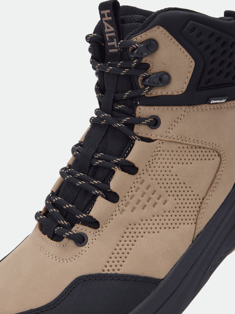 Nahaufnahme des Halti Asento Mid DX Herren-Wanderstiefels in Beige und Schwarz mit schwarzen Schnürsenkeln und Metallösen, aus einem schrägen Blickwinkel.