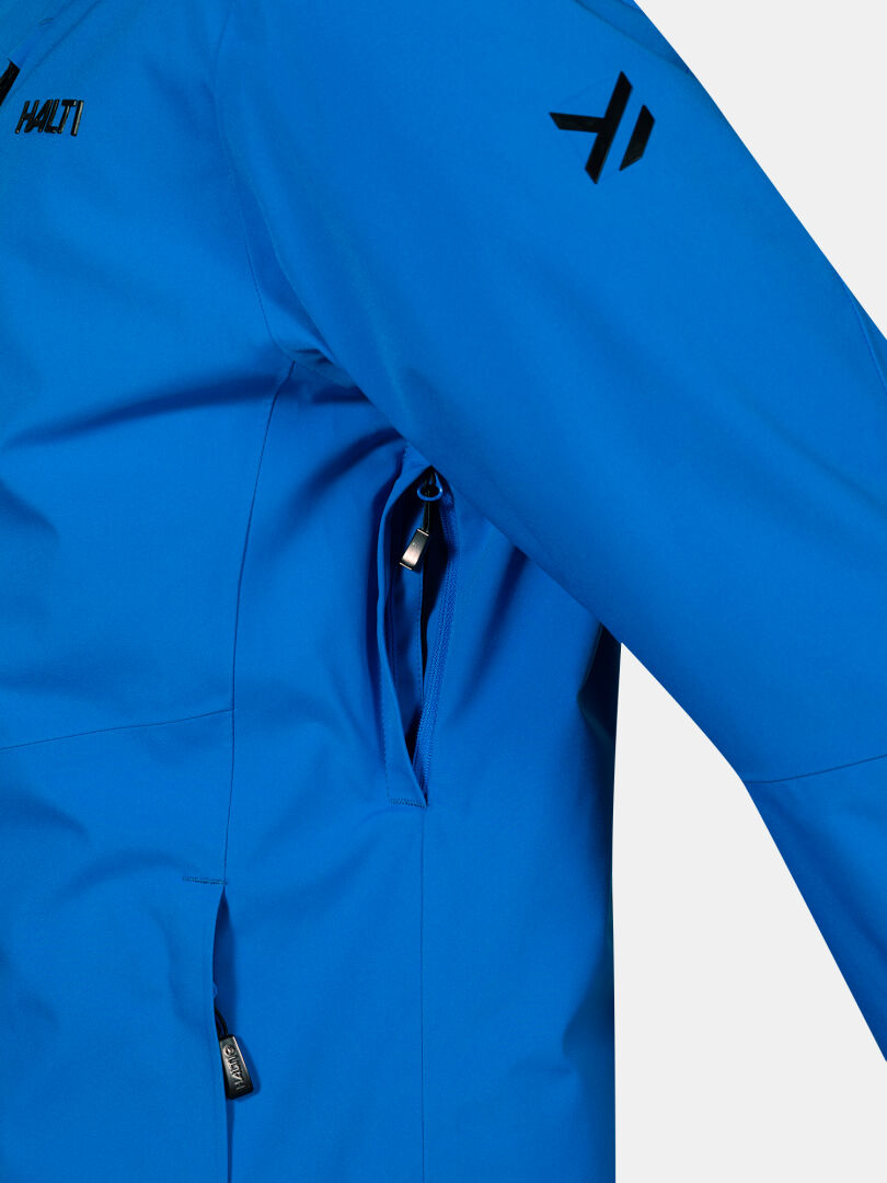 Nahaufnahme der Halti Vertica DX Skijacke Herren in blau mit Vier-Wege-Stretch, seitlich offenem Reißverschluss und schwarzen Logodetails.