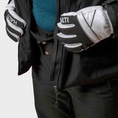 Er trägt eine schwarze Halti Vertica DX Skijacke Herren mit Primaloft Silver und öffnet den Reißverschluss, um ein blaues Hemd darunter zu zeigen.