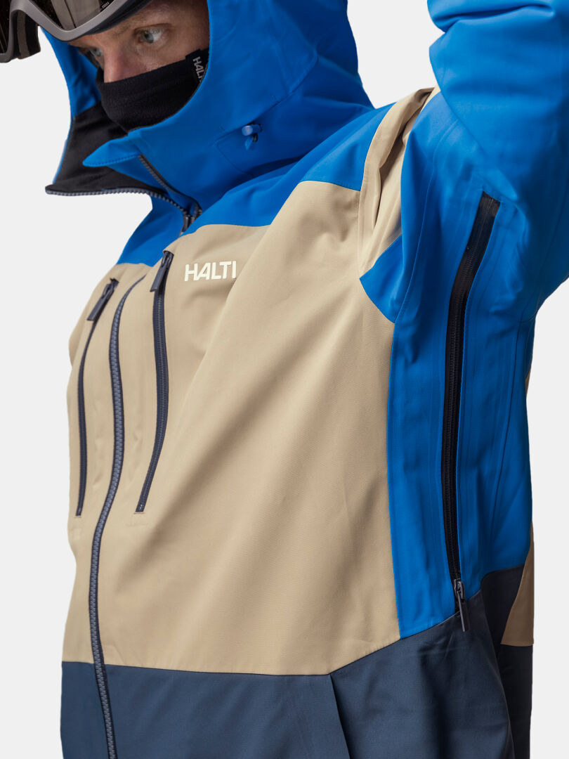 Person in Halti Rizle Unisex 3L DX Skijacke, Kapuze auf, DrymaxX Nano Ärmelreißverschluss einstellen.