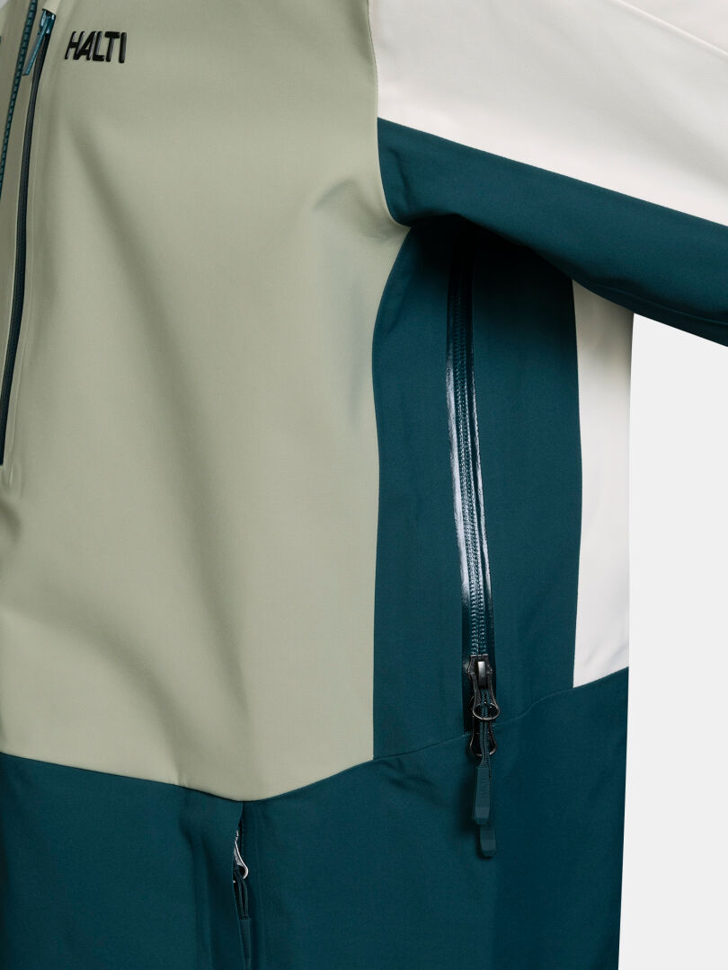 Nahaufnahme einer Halti Rizle Unisex 3L DX Skijacke im Color-Blocking-Design mit einer Reißverschlusstasche.