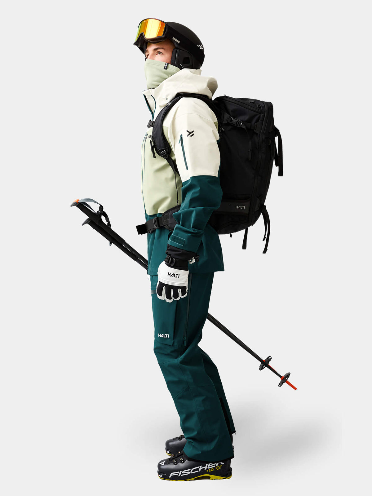 Skifahrer, bekleidet mit einer Halti Rizle Unisex 3L DX Skijacke, einer dazu passenden Hose, einem Helm, einer Skibrille, einem Rucksack und Skistöcken.