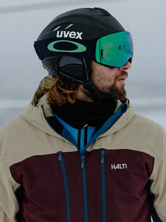 Eine Person mit Helm und Skibrille trägt eine Halti Melvik DX Skijacke Herren im Freien bei verschneiten Bedingungen.