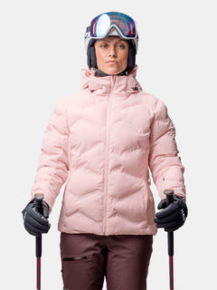 Person in Halti Nordic Arcty II Skijacke Damen, braune Hose, Helm und Brille, hält Skistöcke, Blick nach vorne.