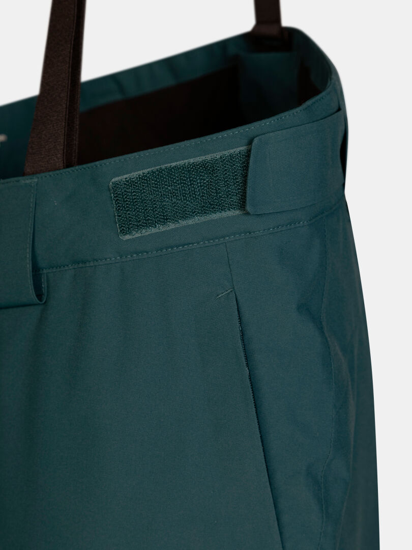 Dunkelgrüne Halti Carvey II DX Skihose für Damen mit einem verstellbaren Klettverschluss am Bund und schwarzen Hosenträgern.