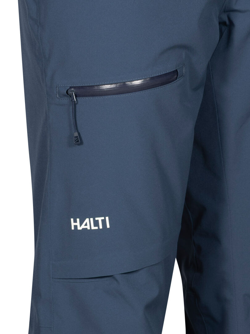 Nahaufnahme der Halti Carvey II DX Skihose Herren in marineblau mit Reißverschlusstasche, DrymaxX-Technologie und weißem Logo am linken Bein.