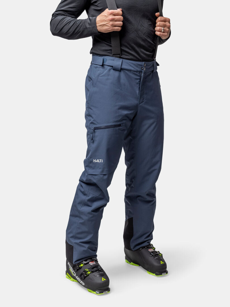 Eine Person modelliert Halti Carvey II DX Skihose Herren und Skischuhe, perfekt für jedes Wintersportabenteuer.