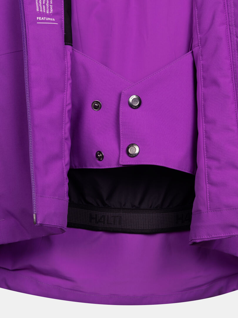 Nahaufnahme einer offenen, violetten Melvik DX Skijacke für Damen mit einem geknöpften Schneefang und einer elastischen Taillenmanschette.