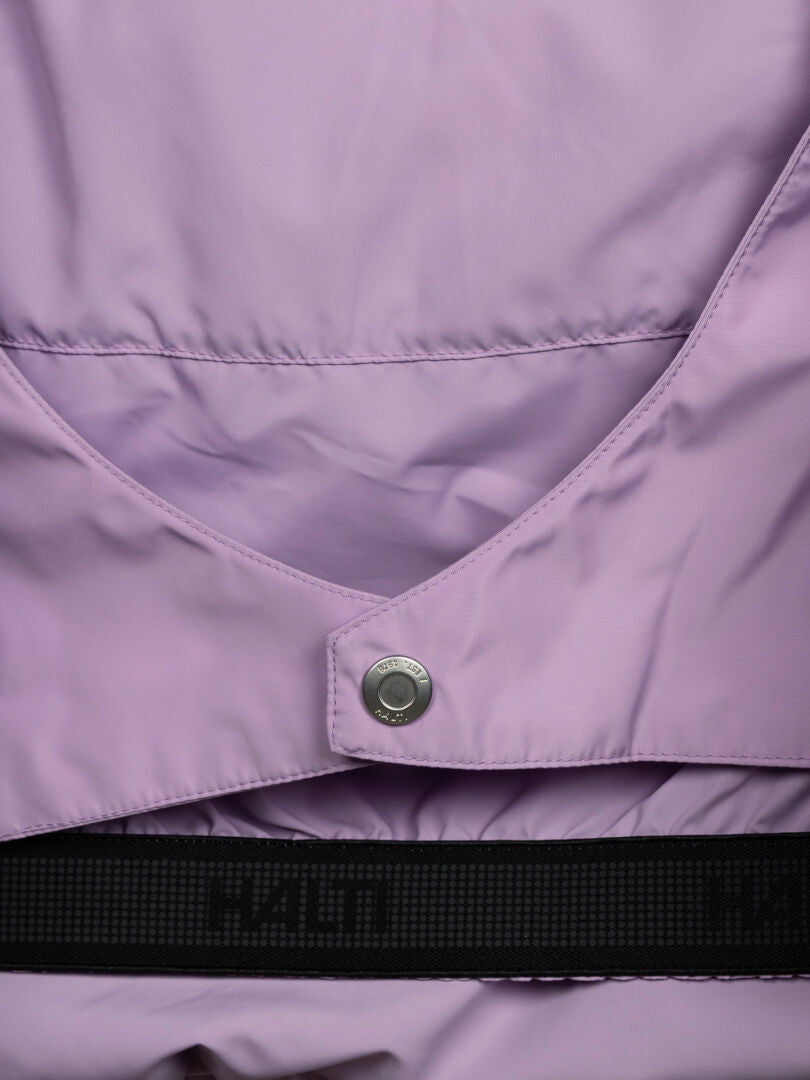 Nahaufnahme einer lavendelfarbenen Halti Ascloud Puffer Skijacke für Damen mit silbernem Druckknopf und schwarzem Riemen mit erhabener Aufschrift.