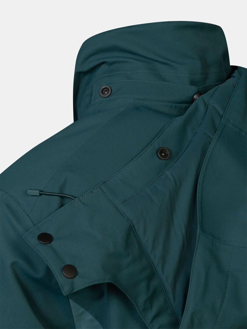 Nahaufnahme des Kragens einer dunkelblaugrünen Halti Recier DX Skijacke für Herren mit Druckknöpfen und einem Kordelzug zur Kapuzenverstellung.