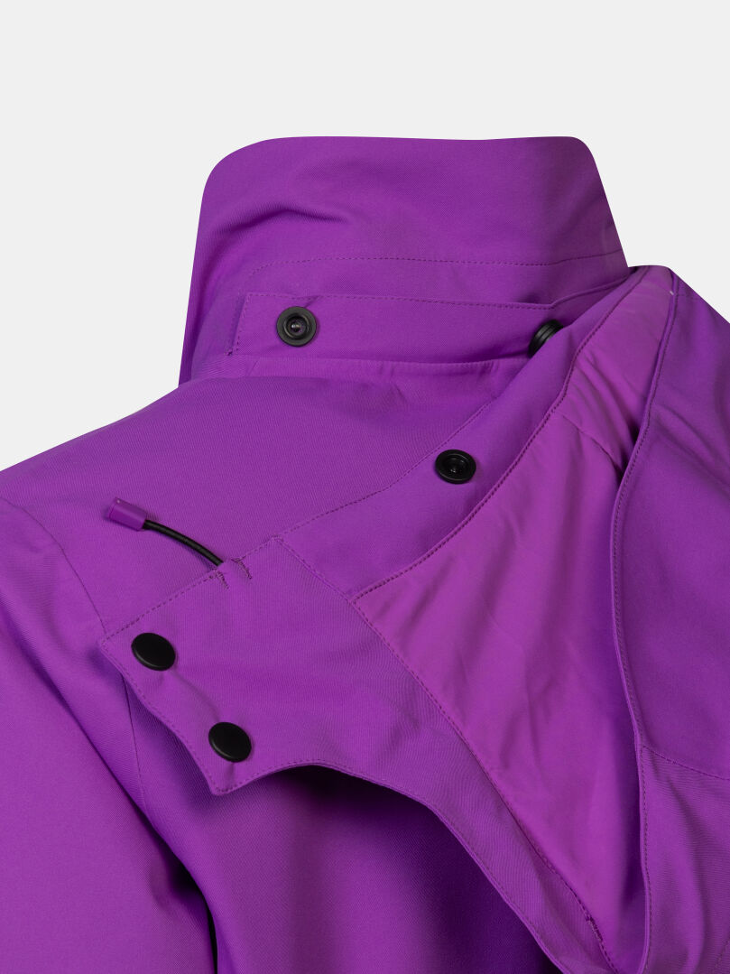 Nahaufnahme eines violetten Kragens der Halti Recier DX Skijacke für Damen mit einer abnehmbaren Kapuze, die mit schwarzen Druckknöpfen befestigt ist.