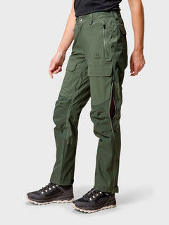 Eine Person in Halti Hiker DrymaxX 3L Ventilated Damen Hose, schwarzem Hemd und schwarzen Wanderschuhen steht vor einem schlichten Hintergrund.