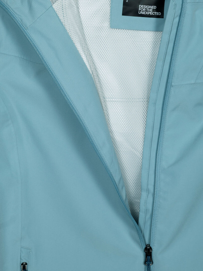 Halti Forter DX Regenjacke für Damen in Hellblau mit offenem Reißverschluss, weißem Netzfutter und sichtbarem schwarzem Markenetikett.
