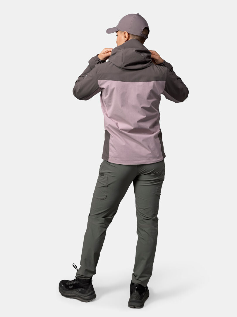 Eine Person in einer Halti Pallas Evo X-Stretch-Jacke Damen, einer grauen Hose und einer Mütze schaut weg und verstellt ihre Kapuze.