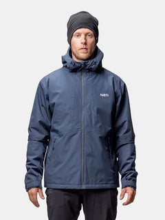 Ein Mann trägt eine Halti Forter DX Warm Regenjacke Herren und eine schwarze Mütze, mit Blick nach vorne vor einem schlichten Hintergrund.