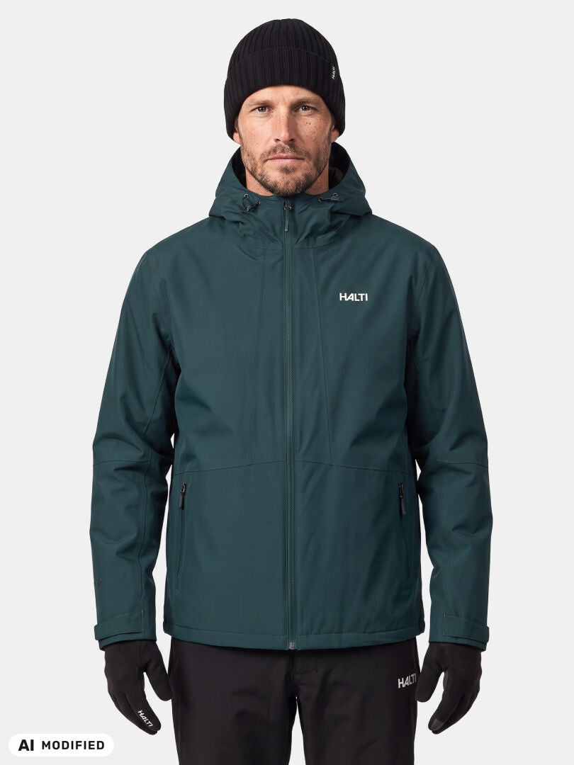 Ein Mann in einer dunkelgrünen Halti Forter DX Warm Regenjacke, schwarzen Handschuhen, einer schwarzen Hose und einer schwarzen Mütze steht mit dem Gesicht nach vorne.