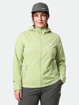 Eine Person in einer grünen „Halti Forter DX Regenjacke Damen Plus“ und einer grauen Mütze steht da und hat eine Hand in der Tasche.