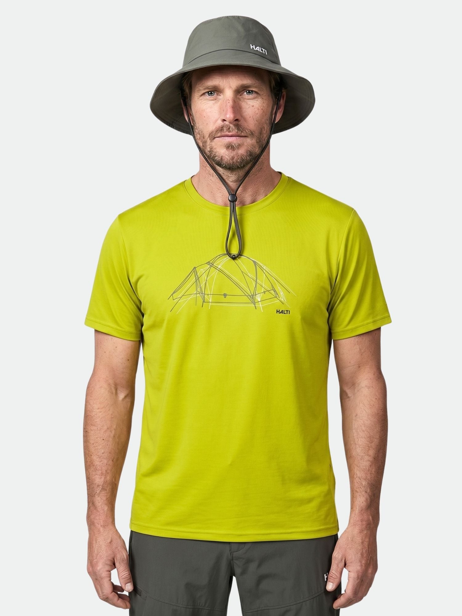 Ein Mann trägt ein Halti Kalteva T-Shirt Herren mit Zeltgrafik, einen grauen Hut mit Kinnriemen und eine graue Outdoor-Hose.