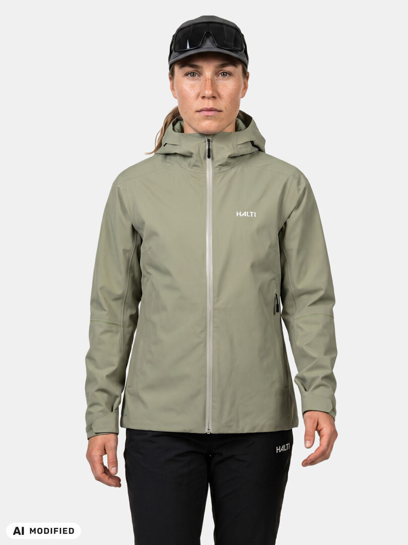 Eine Person, die die olivfarbene „Staala DX Regenjacke Damen“ von Halti, eine schwarze Hose und eine Mütze trägt, ist bereit für ein Outdoor-Abenteuer.