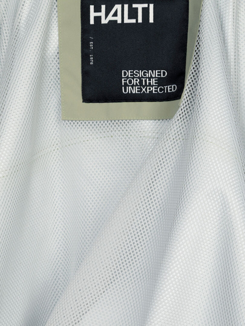 Nahaufnahme des grauen Netzgewebes an der Staala DX Regenjacke für Damen, mit einem schwarzen Halti-Etikett mit der Aufschrift „DESIGNED FOR THE UNEXPECTED“.