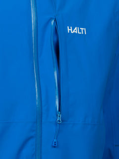 Nahaufnahme der Halti Staala DX Regenjacke Herren, einer blauen wasserdichten Jacke mit Brusttasche mit Reißverschluss und weißem Logo.