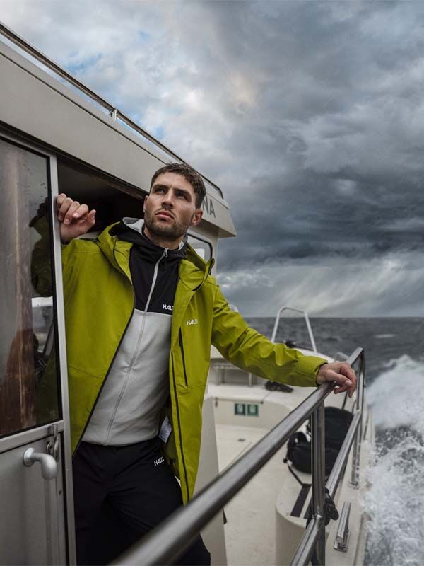 Ein Mann in einer Halti Staala DX Regenjacke Herren steht auf einem Boot.