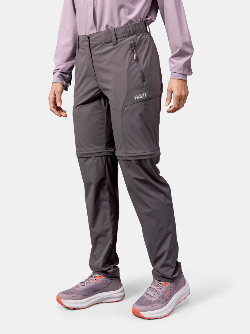 Person trägt Halti Pallas Cool Stretch Zip-off Hosen Damen, ein langärmeliges Hemd und lila Turnschuhe.