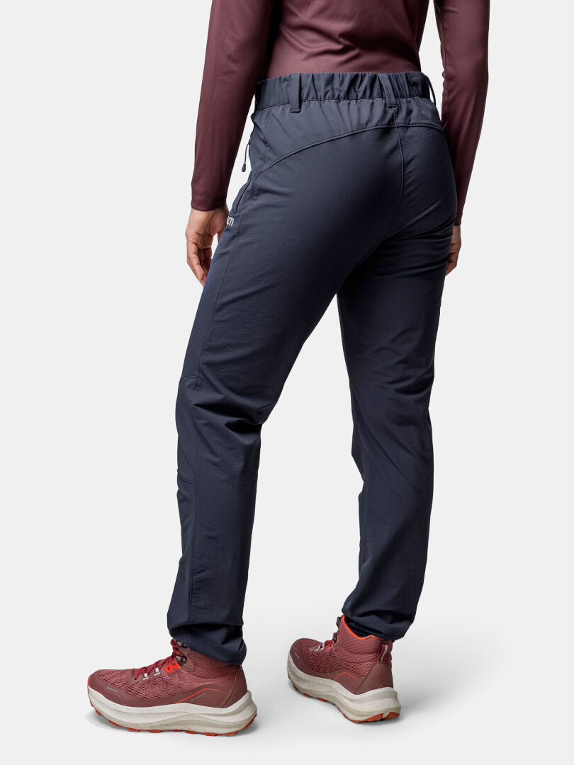 Frau in Halti Finholma X-stretch Hose, Stretchmaterial, kastanienbraunes Shirt & Sneakers, bereit für Outdoor-Aktivitäten von hinten.