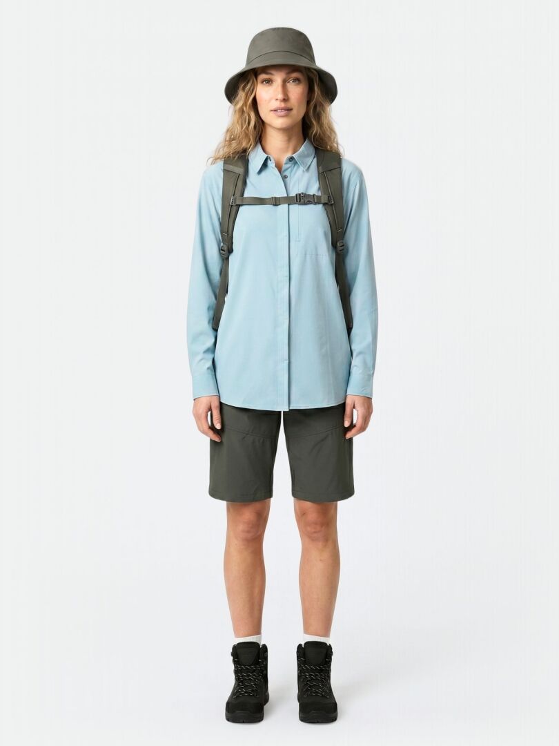 Person in Halti Samoy Langarm Funktionshemd Damen, dunklen Shorts, Wanderschuhen, grauer Mütze und Rucksack mit Blick nach vorne.