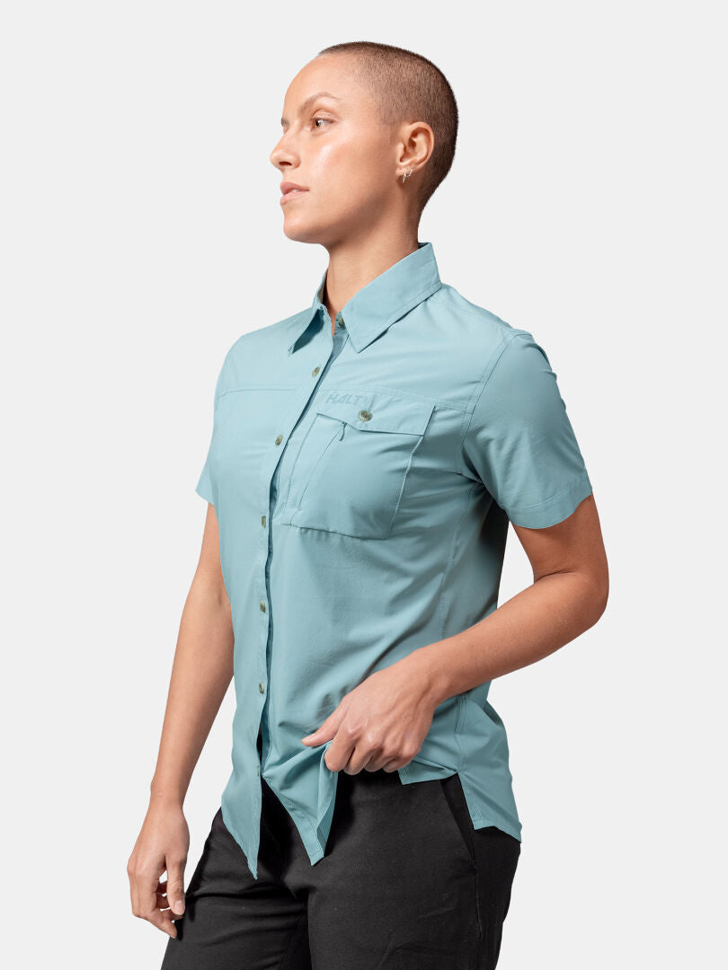 Eine Person mit kurzen Haaren trägt das Halti Samoy Funktionshemd Damen und eine schwarze Hose und steht vor einem schlichten Hintergrund.