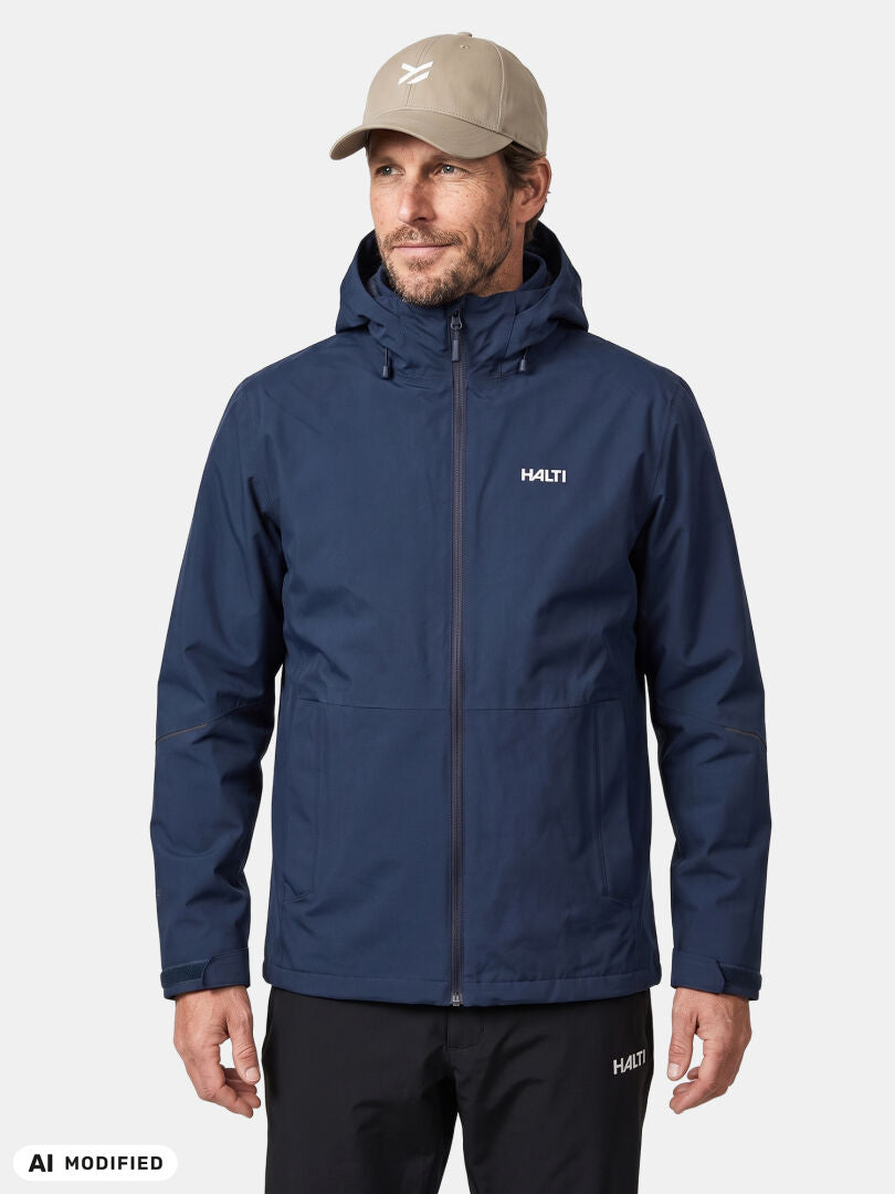 Ein Mann in einer „Halti Loito 3-in-1 DX“-Jacke für Herren, einer beigen Mütze und einer schwarzen Hose steht mit dem Gesicht nach vorne vor einem einfarbigen Hintergrund.