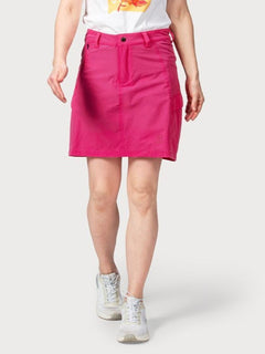 Person, die ein weißes T-Shirt, Halti Reissu Damen Stretch Rock in leuchtendem Pink und weiße Turnschuhe vor einem unifarbenen Hintergrund trägt.
