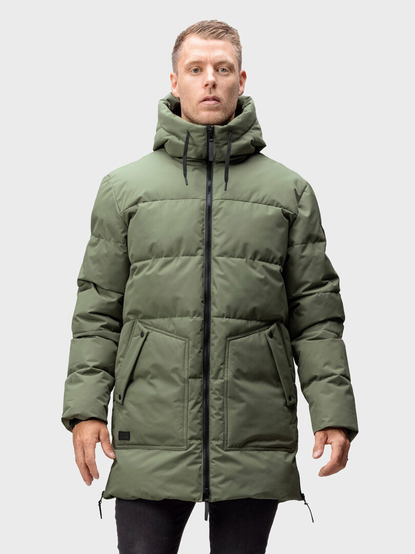 Ein Mann trägt die Halti Linjat Parka Jacke Herren in Grün mit Thermofill-Isolierung, schwarzem Reißverschluss und Taschen.