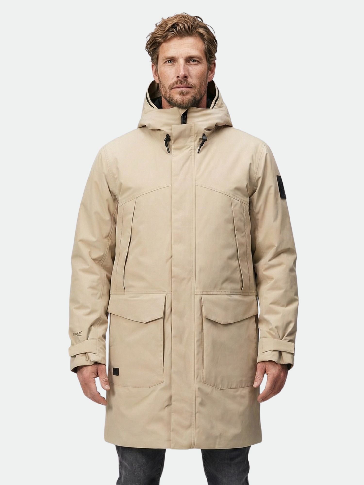 Ein Mann trägt den Halti Bergga DX Winter Parka Herren in Beige vor einem schlichten hellen Hintergrund.