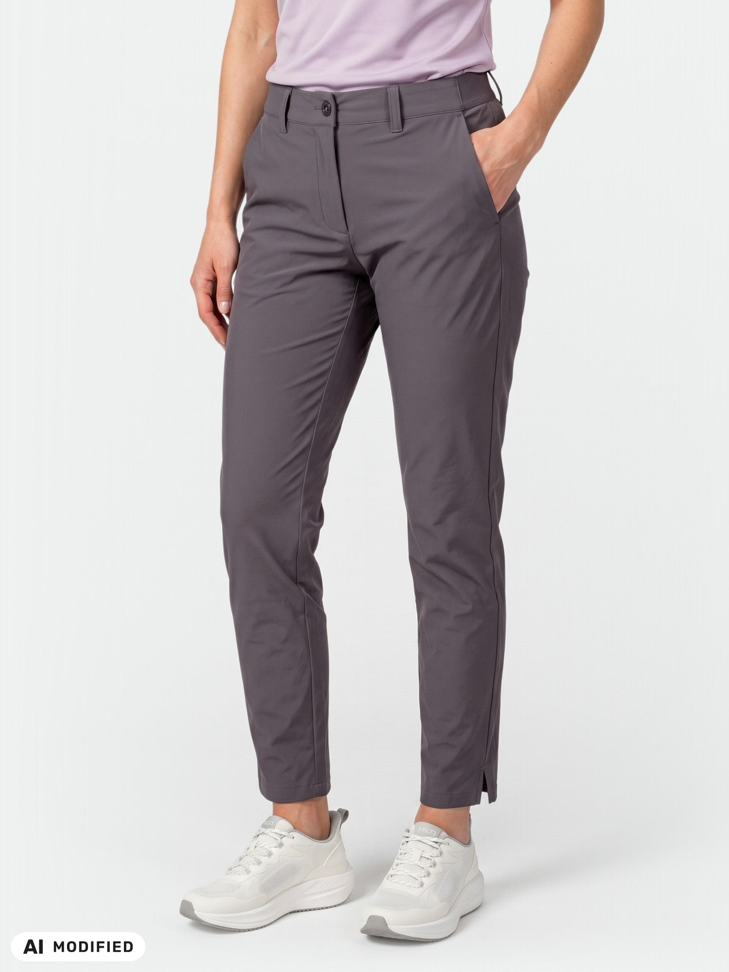 Das Model trägt eine Halti Drive X-Stretch-Chino für Damen (grau), ein hellviolettes Hemd und weiße Sneaker, die Hände in den Taschen.