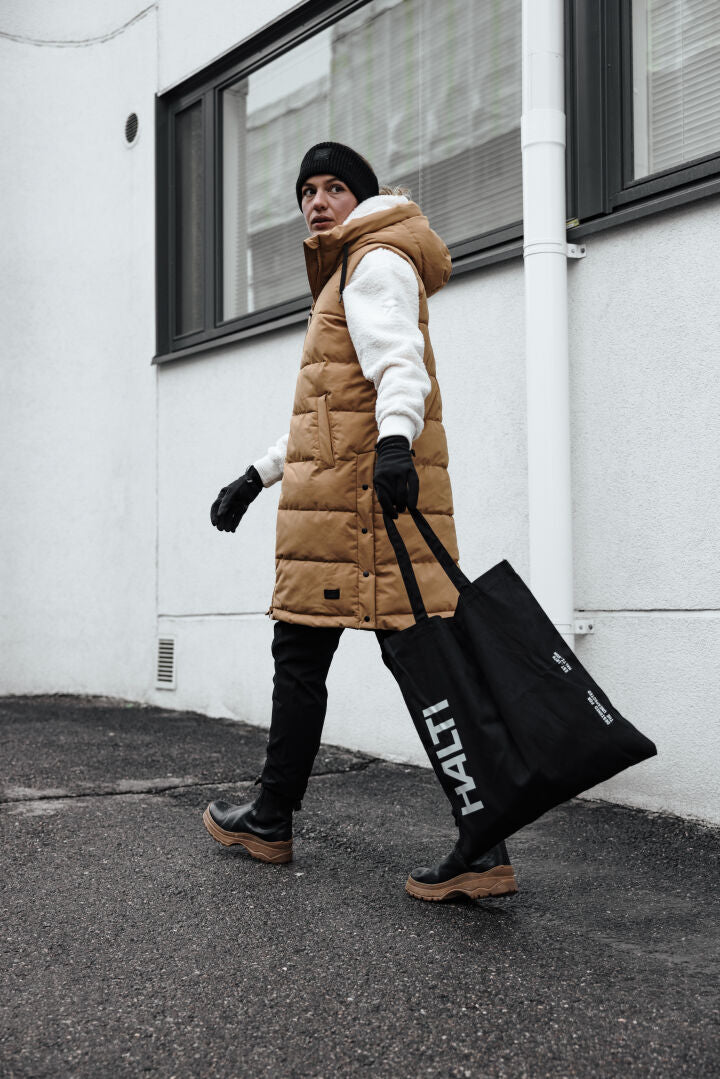 Person in hellbrauner Pufferweste und Halti Lykky Fleecepullover Damen geht mit einer großen schwarzen Halti Tragetasche nach draußen.
