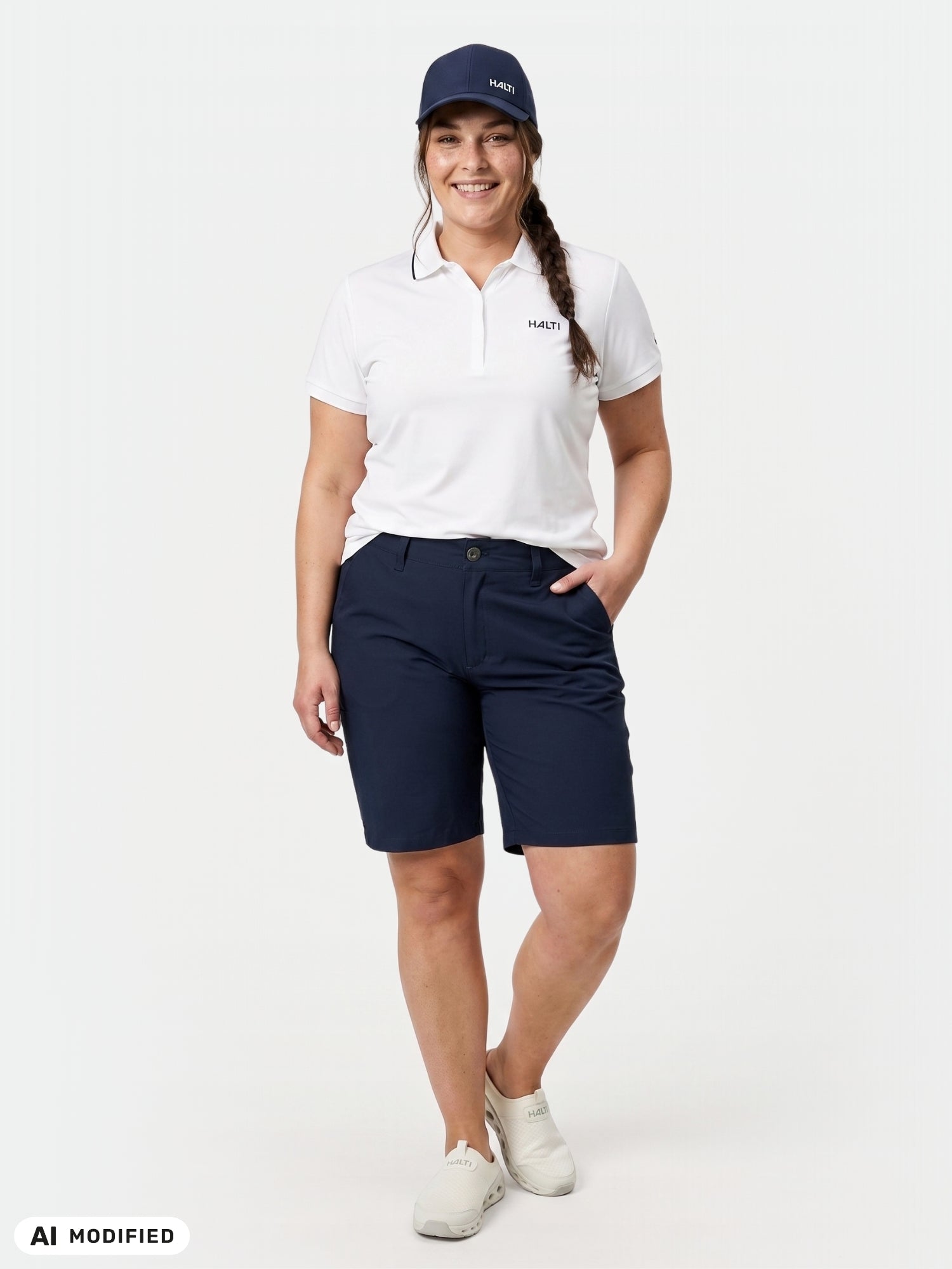 Eine Frau in „Halti Drive X-Stretch Shorts Damen Plus“ und einer Mütze lächelt selbstbewusst vor einem schlichten, hellen Hintergrund.