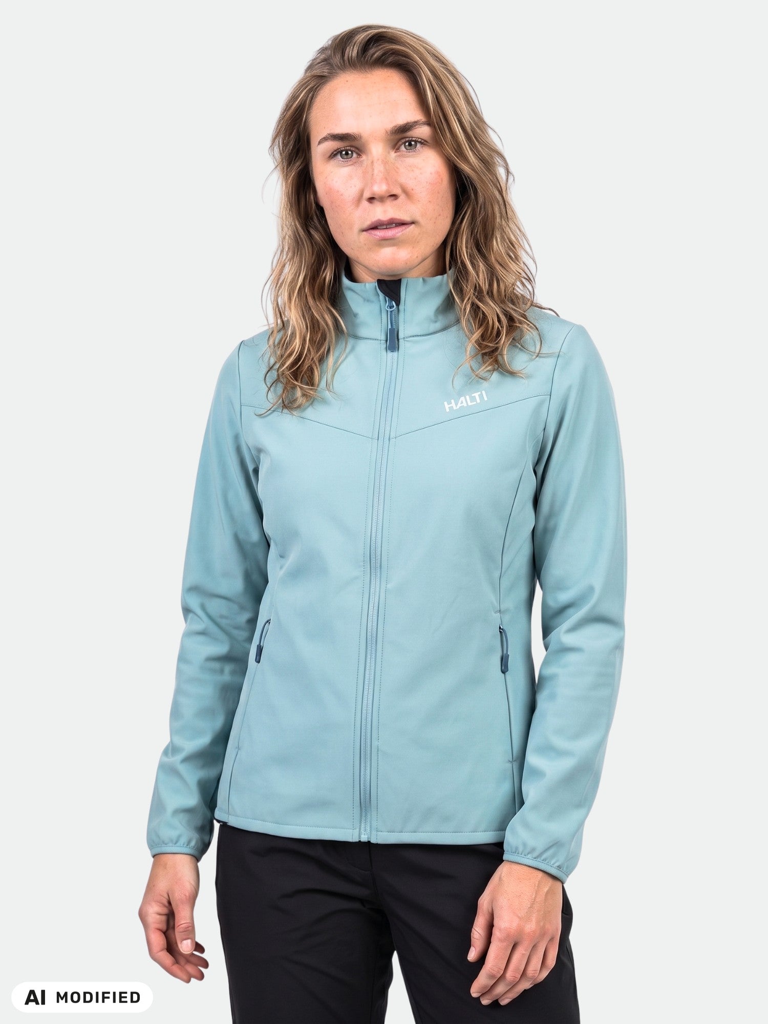 Eine Frau in einer „Halti Wedge Softshell Jacke“ für Damen, ideal für Outdoor-Aktivitäten, steht vor einem weißen Hintergrund.