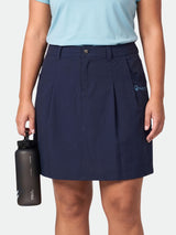 Eine Person, die einen marineblauen Rock „Halti Drive X-Stretch Rock Damen Plus“ und ein hellblaues Hemd trägt, hält mit der linken Hand eine schwarze Wasserflasche in der Hand.