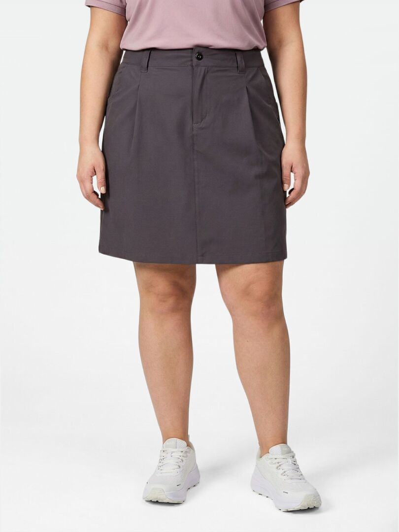 Eine Person trägt ein lilafarbenes Hemd, Halti Drive X-stretch Rock Damen Plus in Dunkelgrau, und weiße Turnschuhe vor einem unifarbenen Hintergrund.