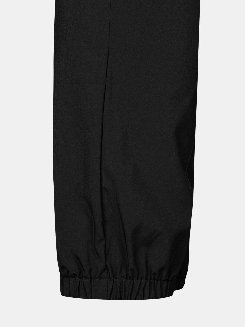 Nahaufnahme der schwarzen Halti Grets Joggers Herren mit elastischen Knöchelbündchen, dargestellt vor einem schlichten hellen Hintergrund.