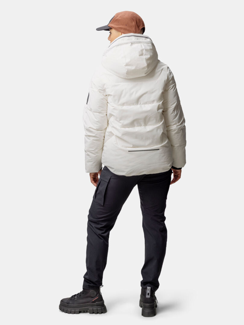 Frau in Halti Brahe Puffer Winterjacke aus recyceltem Polyester, schwarzer Hose und brauner Mütze steht mit dem Rücken zur Kamera.