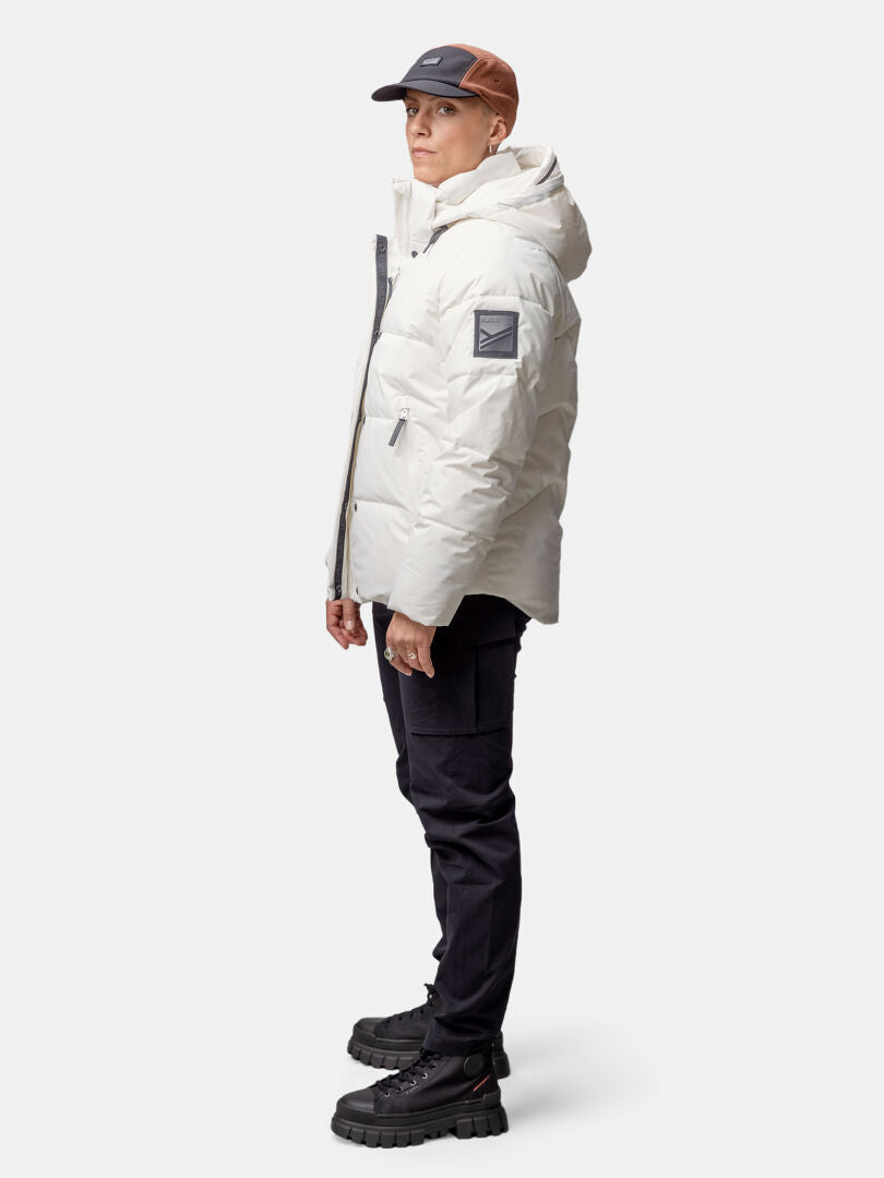 Person in der weißen Halti Brahe Puffer Winterjacke aus recyceltem Polyester, schwarzen Hosen und Boots.